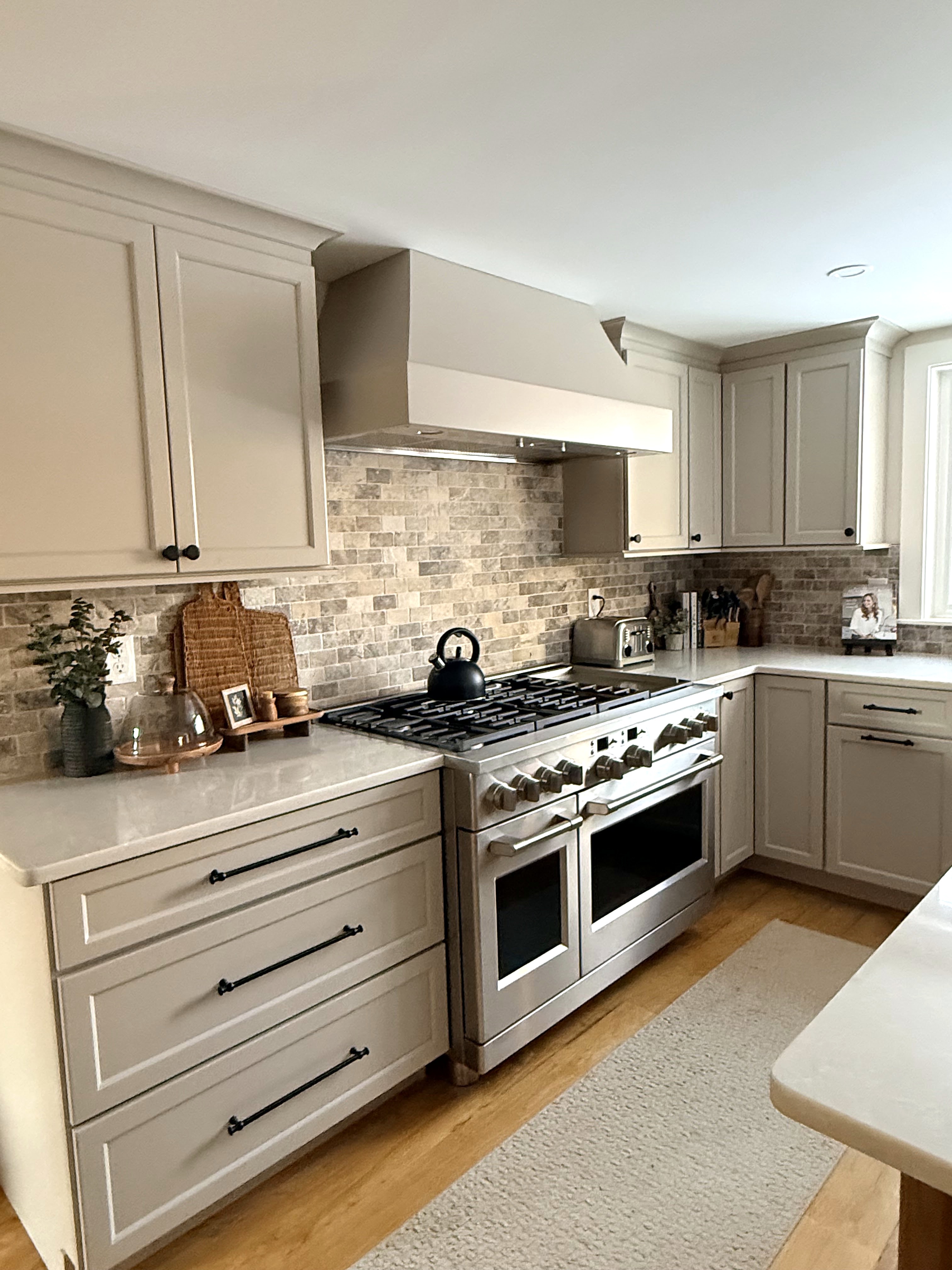 Light kitchen cabinets with a tile backsplash and range hood