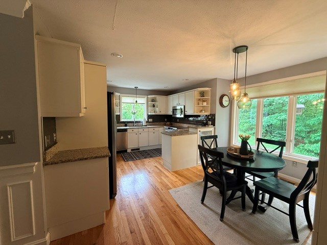 Before: kitchen and dining area with cream cabinets and dark countertops