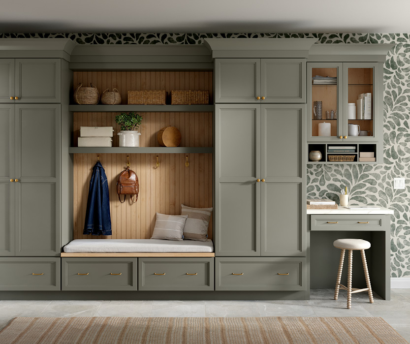 Green painted mudroom built-ins with bench, hooks, drawers and open shelving