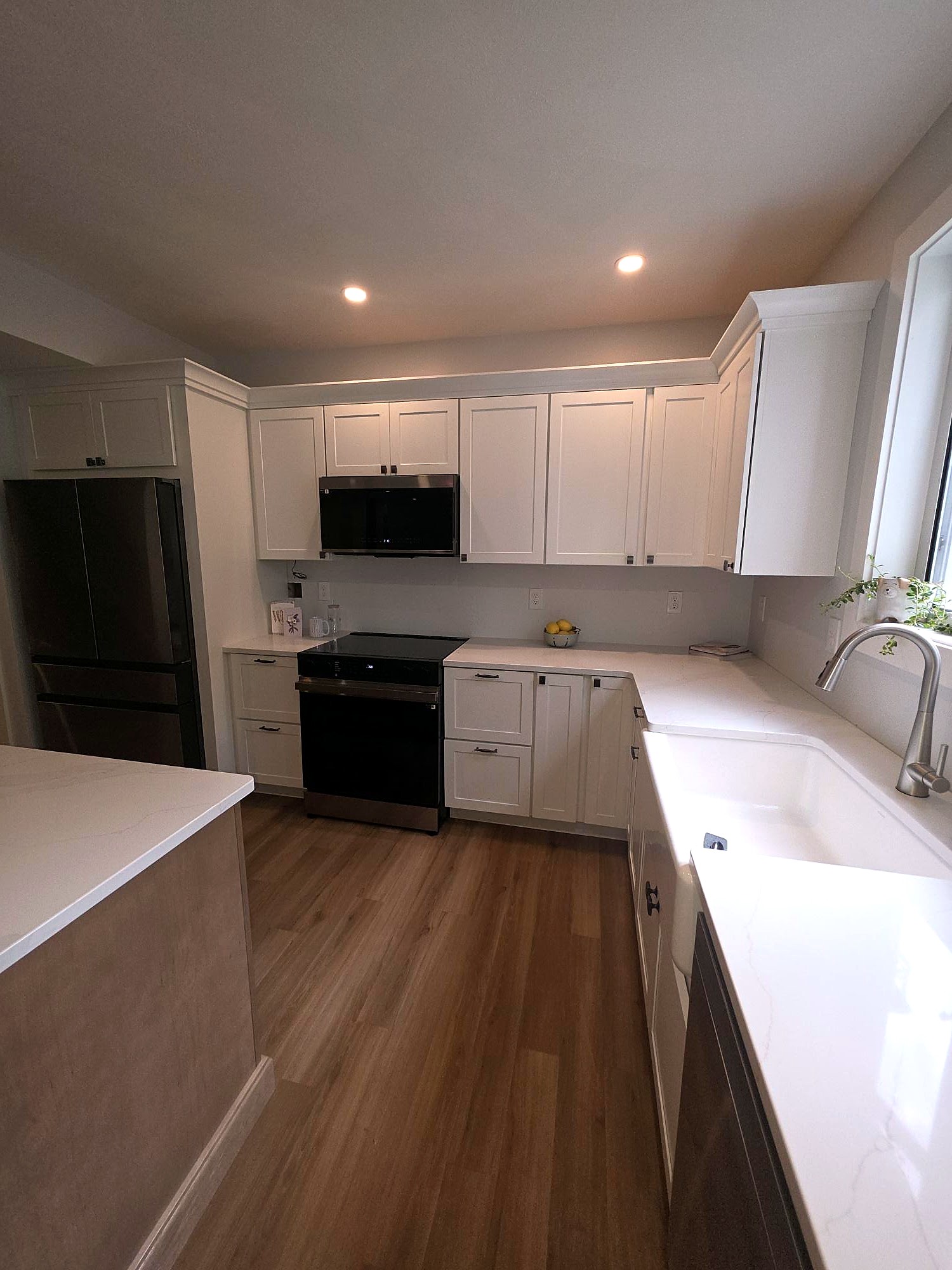 White kitchen cabinetry with a range hood and corner storage