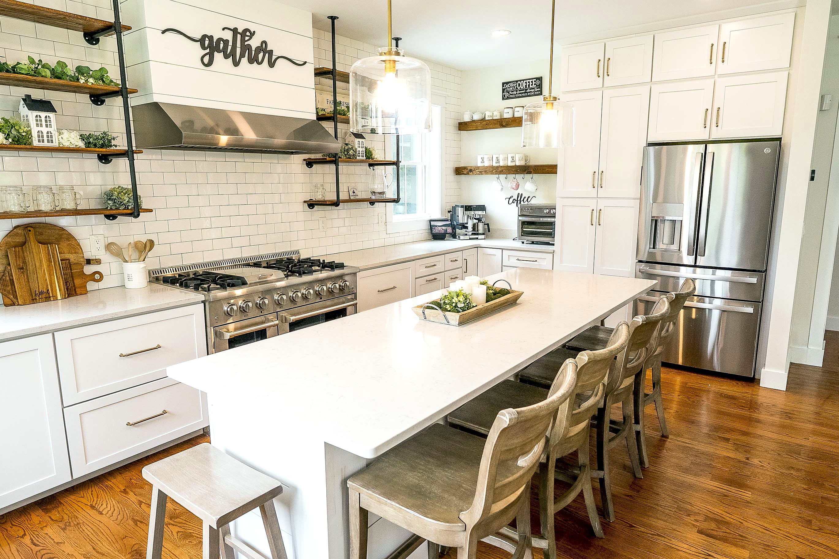 Quartz island, white perimeter cabinetry and floating shelves