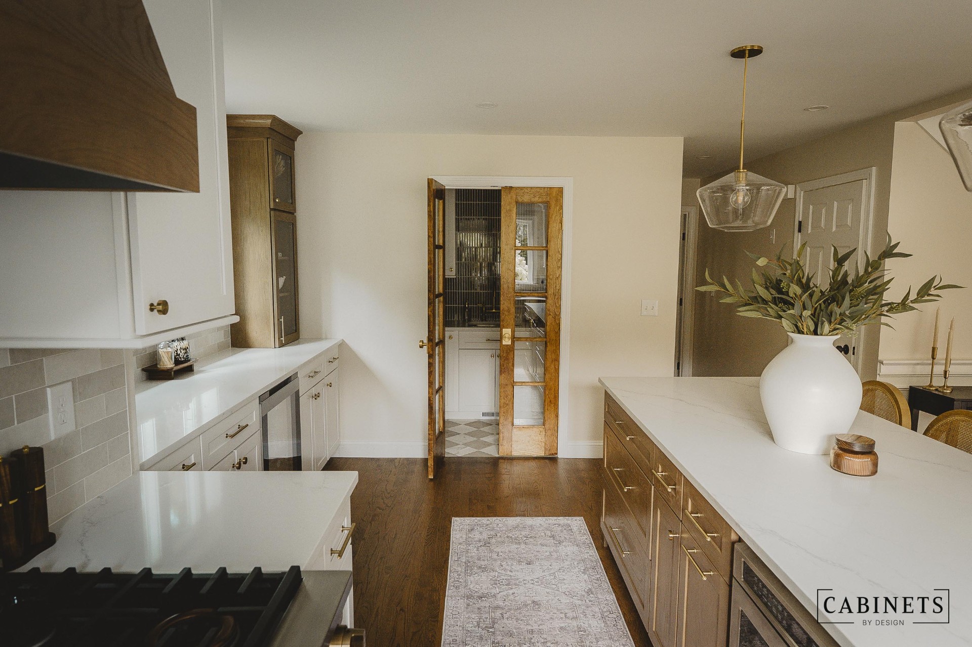 After: glass-front stained display cabinets and a walk-in pantry behind wood french doors